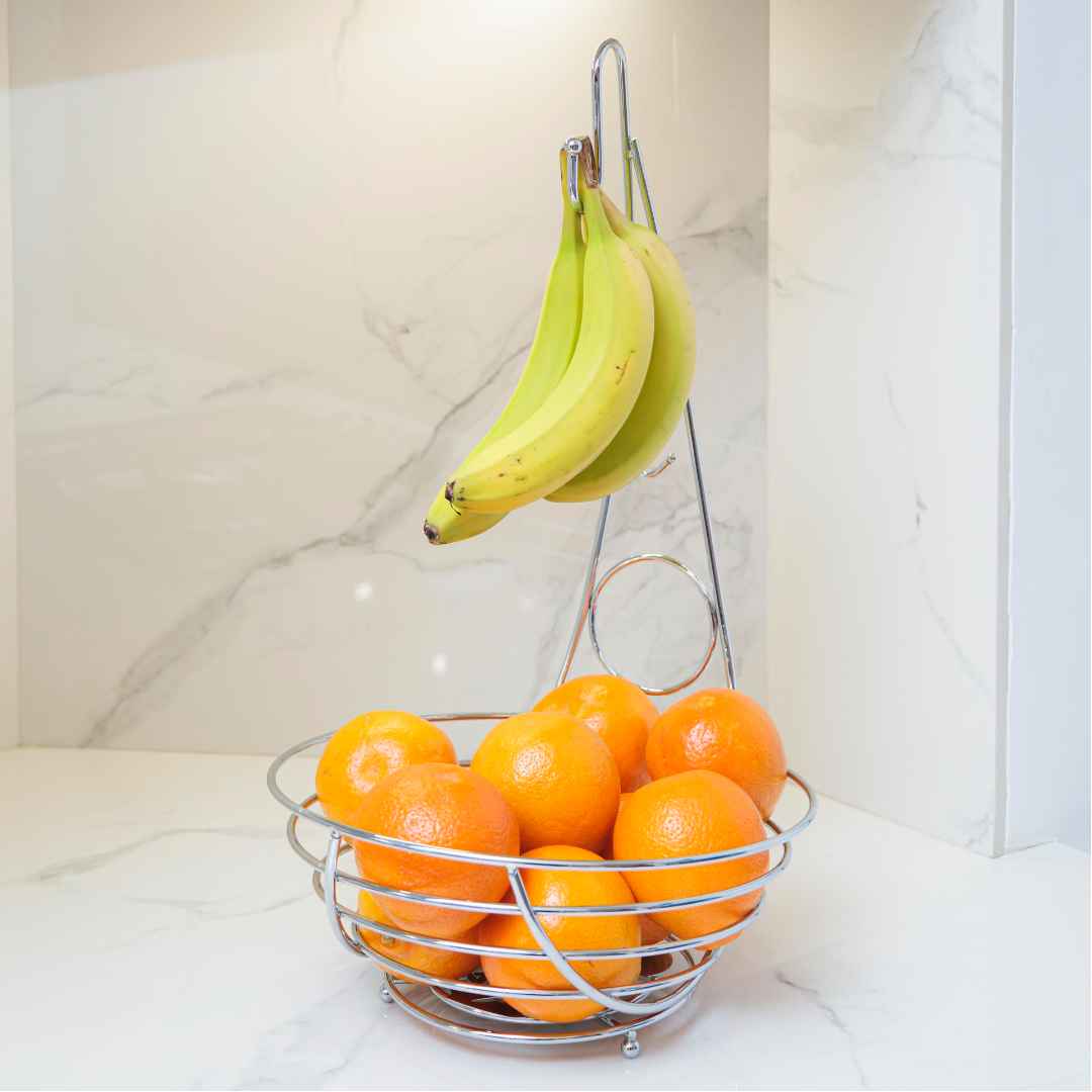 Frutero de metal cromado con bananas y naranjas.