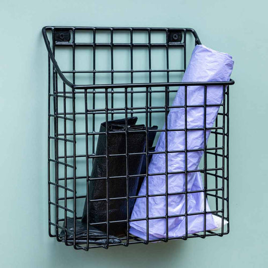 Canasta para bolsas en color negro, instalada en una pared con bolsas guardadas