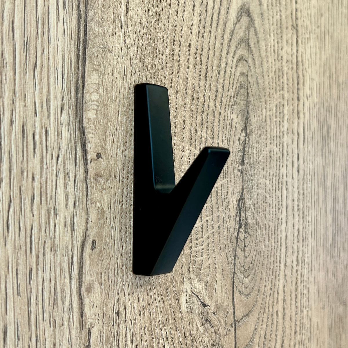 Colgador perchero 45° negro y vacío sobre un panel de madera
