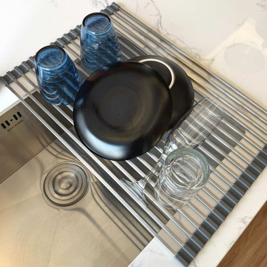 Escurridor flexible con platos y vasos sobre el lavadero