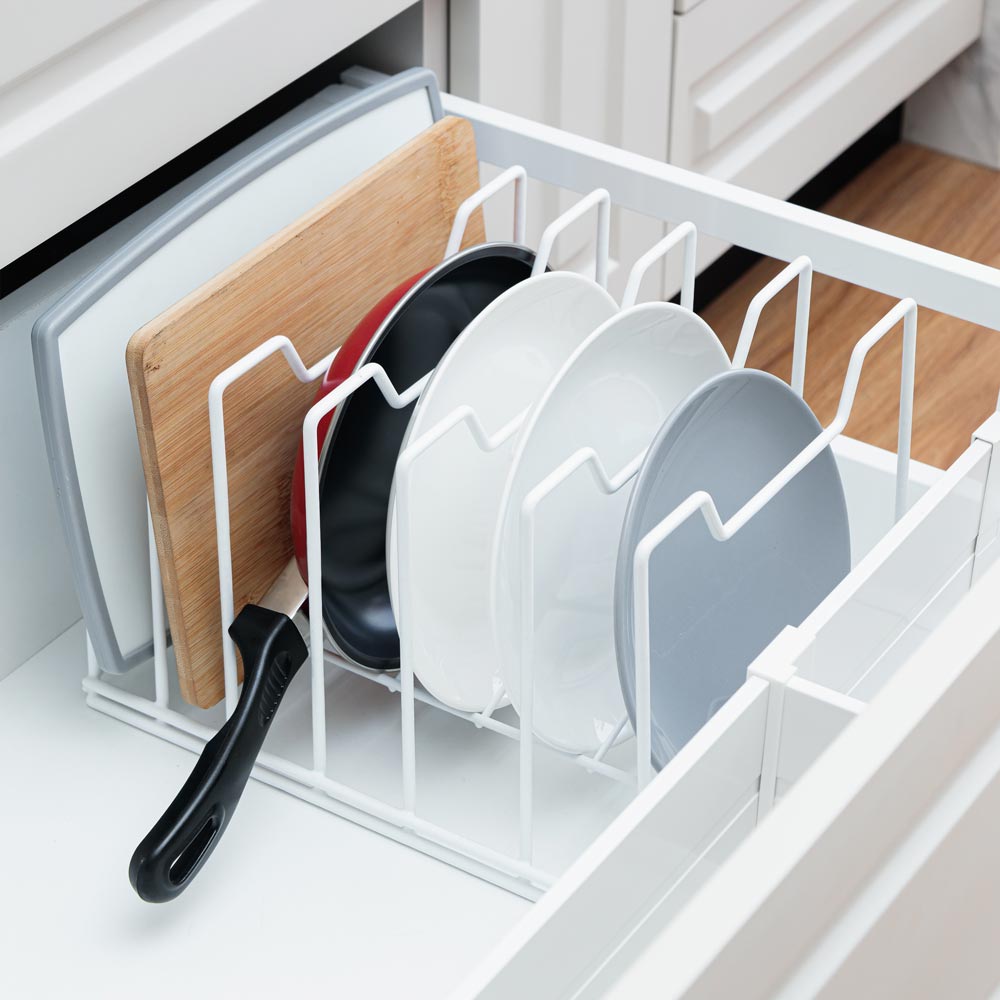 Organizador multifunción en color blanco, con platos, sartén y tablas dentro de un cajón