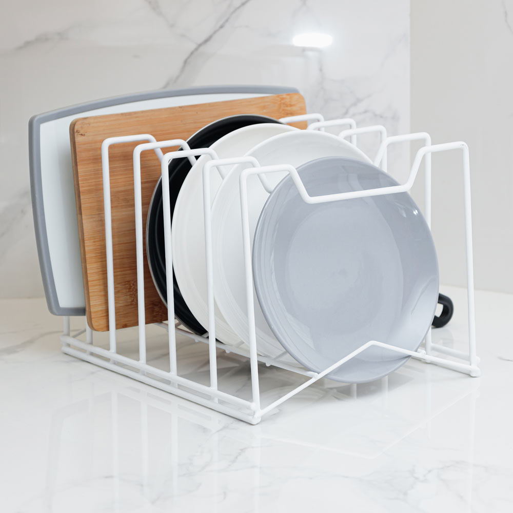 Organizador multifunción en color blanco, con tablas, tapas y utensilios de cocina sobre una encimera