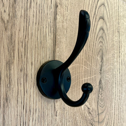 Percha decorativa negra y vacía sobre un panel de madera
