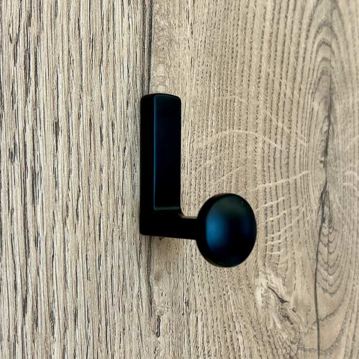 Percha en L negra y vacía sobre un panel de madera