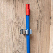 Porta escoba instalado en un panel de madera con un mango sujeto