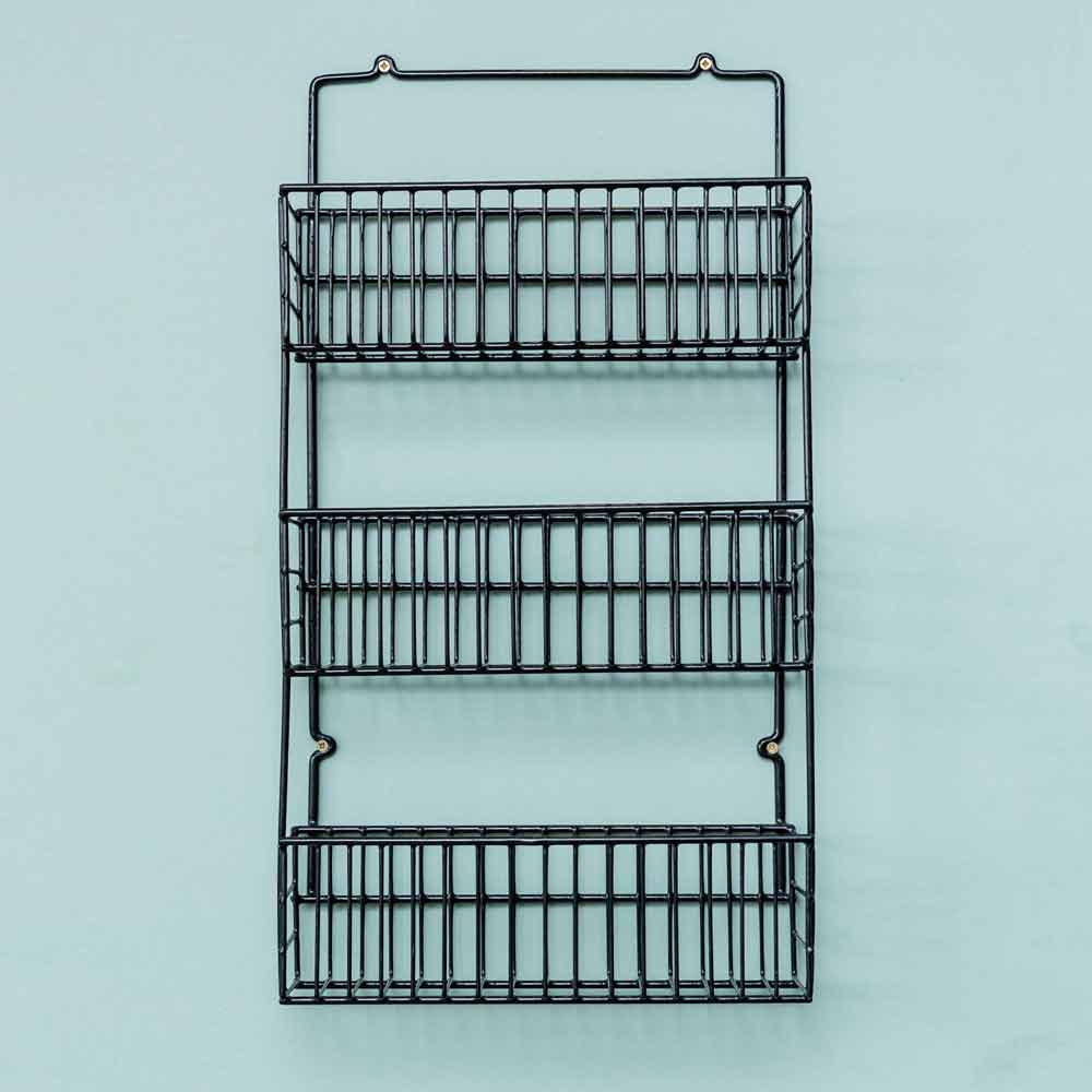 Rack auxiliar en color negro, vacío e instalado en la puerta de un mueble