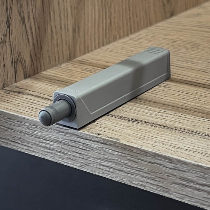 Soporte de amortiguador para puertas de mobiliario y de sistema push to open montado sobre una superficie de madera